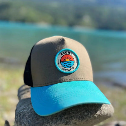 image de notre casquette trucker surf avec la visière bleu turquoise et le reste kaki et le filet noir.Le logo est brodé à l'avant et à l'arrière il est brodé le slogan BE ALOHA BE FREE