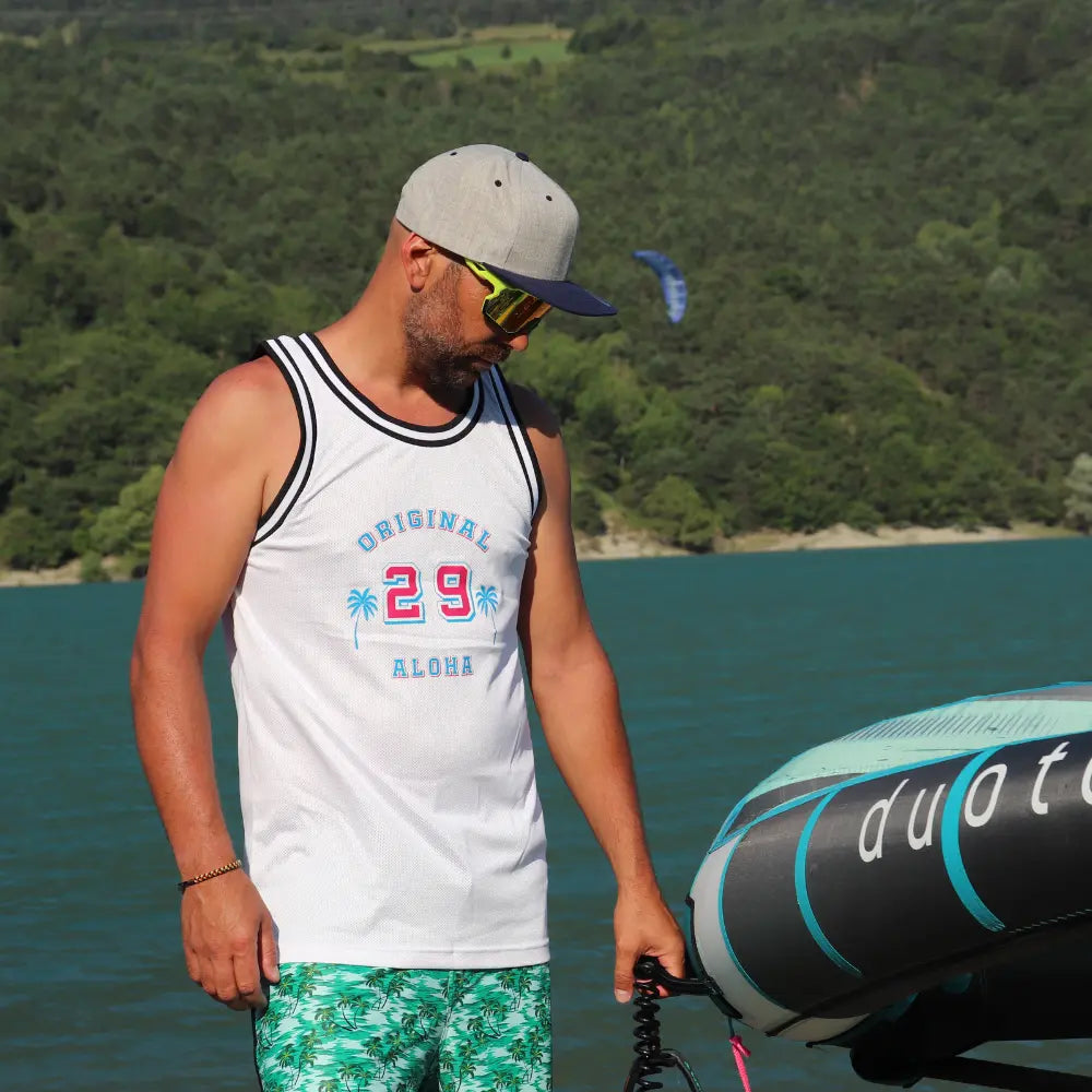 Image d'un débardeur blanc Homme style basketteur avec  un logo avec des palmier et le chiffre 29  dans une matière style filet de la marque Alohasurfwear